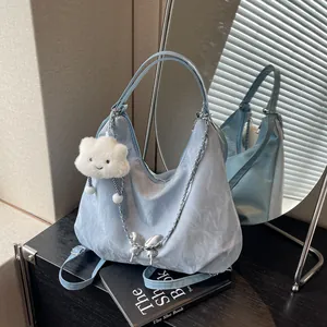 Detailed view of blue metallic hobo bag with silver chain butterfly and plush charm