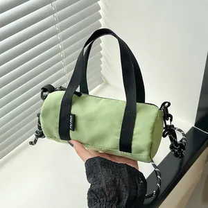 Close-up of light green mini cylinder bag with black straps and zipper details