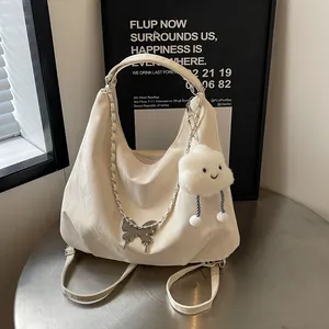Detail of off-white pleated tote bag featuring silver butterfly and plush cloud charms