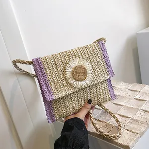Close-up of a woven straw bag featuring purple patchwork and a large white daisy flower