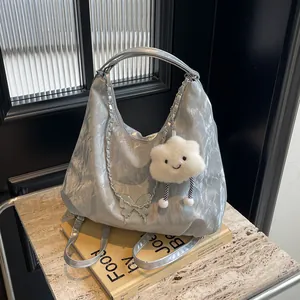 Macro shot of silver crinkle textured tote bag featuring butterfly chain and plush charm