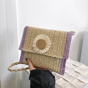 Close-up of handmade straw crossbody bag with daisy flower and purple woven trim details