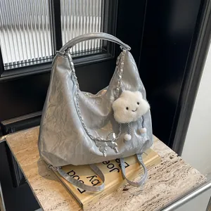 Detail of silver metallic tote bag featuring chunky metal chain and butterfly pendant