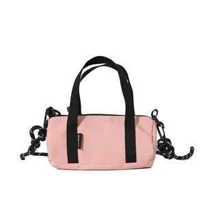 Mini pink cylindrical oxford crossbody bag with black handles and woven rope strap