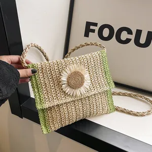 Detail of hand-woven straw bag with a large white daisy flower and green woven accents