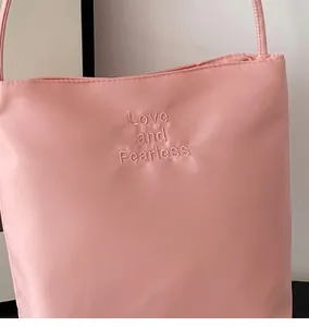 Détail du sac en satin rose avec broderie Love and Fearless et bandoulière fine
