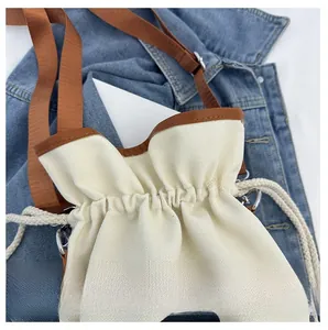 Detail view of the canvas bucket bag showing the drawstring closure and brown leather trim