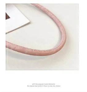 Détail de la bandoulière en cuir rose avec coutures fines semi-circulaires artisanales