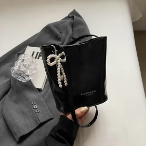 Detail of glossy black bucket bag with pearl bow charm and Fashion & Bags text logo