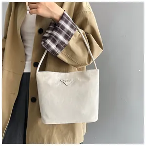 Détail d'un sac cabas plissé beige avec plaque triangulaire sur un manteau élégant