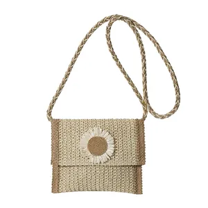 Handwoven straw crossbody bag with brown trim and a decorative white daisy flower