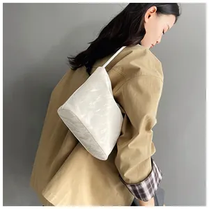 Détail d'un sac à bandoulière blanc avec texture marbrée et design minimaliste