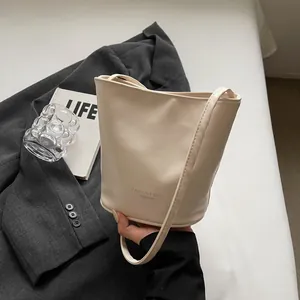 Detail of minimalist cream bucket bag with black fashion text on grey blazer