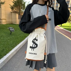 Street style shot of a cream canvas bucket bag with brown leather trim and drawstring