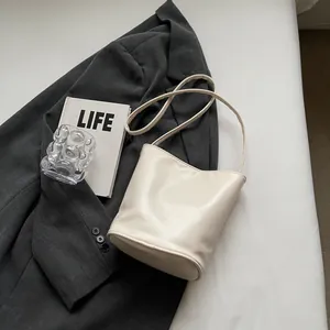 Detail view of a creamy white leather bucket bag with elegant minimalist texture