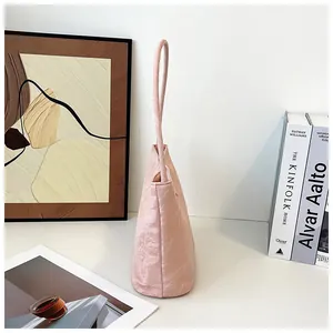 Vue détaillée d'un sac à main rose clair avec longue poignée et tissu texturé