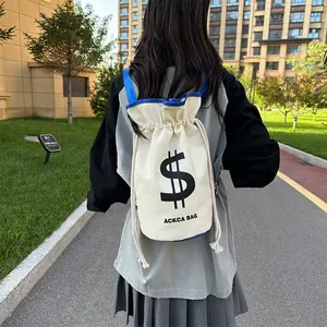 Outdoor shot of ivory canvas drawstring bucket bag with navy blue trim and strap details