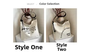 Dettaglio della grande borsa tote in tela con stampa di lettere e nodi decorativi sulla tracolla