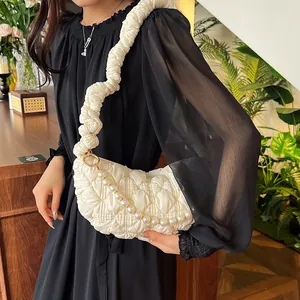 Detail of white quilted underarm bag featuring large pearl chain and ruched cloud strap