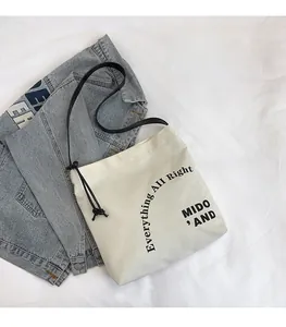 Dettaglio della borsa tote in tela bianco sporco con scritte nere e spalline sottili