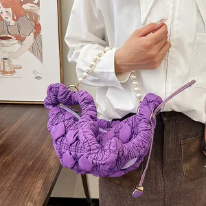 Detail of purple ruched cloud bag featuring elegant large pearl handle and quilted texture