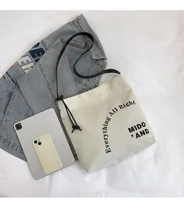 Dettaglio della borsa tote in tela beige confrontata con tablet e smartphone per dimensioni
