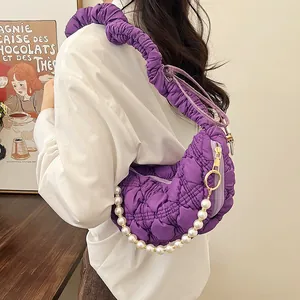 Detail of purple quilted crescent bag with ruffled strap and faux pearl charm