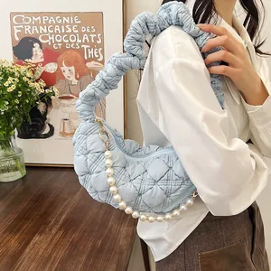 Detail of light blue pleated cloud bag with quilted fabric and elegant pearl strap