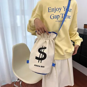 Detail of canvas bucket bag with dollar sign logo and adjustable blue shoulder strap