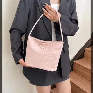 Sac à bandoulière rose plissé avec logo triangulaire en métal porté par un modèle