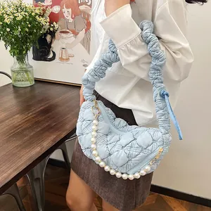 Detail of light blue quilted cloud bag featuring pearl chain and ruched shoulder strap