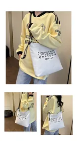 Tre viste di una borsa tote in tela bianca con stampa di lettere nere e coulisse