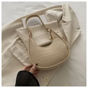 Close-up of beige crescent bag featuring crocodile embossed texture and gold zipper