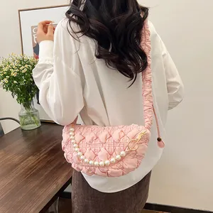 Detail of pink quilted crossbody bag with pearl chain and pleated cloud-like strap