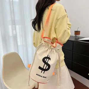 Detail view of canvas bucket bag featuring orange straps and black dollar sign print