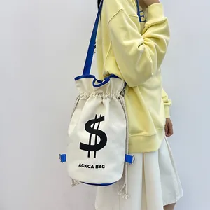 Detail view of canvas drawstring bucket bag with blue straps and dollar sign logo