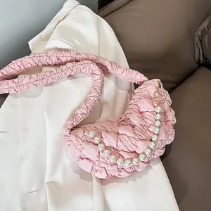 Pink pleated cloud bag with pearl chain detail and textured fabric on white blazer