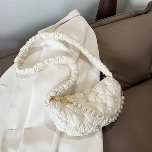 Detail of cream pleated cloud bag featuring decorative pearl chain and golden metal hooks