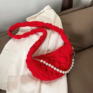Detail of red quilted bubble shoulder bag with elegant pearl chain and textured strap