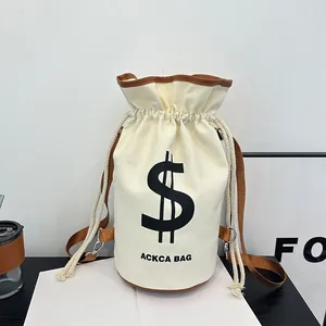 Detail of canvas bucket bag featuring a dollar sign print and brown leather trim accents
