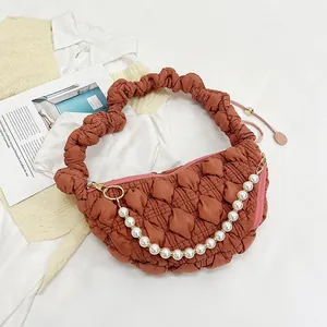 Detail of caramel quilted bubble texture bag featuring white pearls and pleated handle