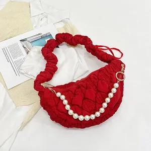 Close-up of red quilted cloud bag with pearl chain strap and pleated fabric texture