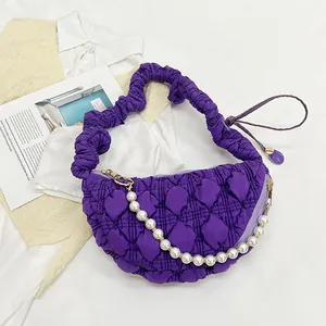 Detail of purple quilted crescent bag featuring pearl chain and ruffled handle strap