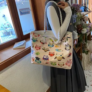 Detail of canvas tote bag featuring colorful owl patterns and thick white rope handles