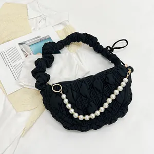 Detail of black pleated cloud bag featuring textured fabric and elegant pearl chain