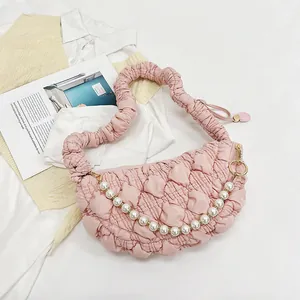 Detail of pink quilted puff shoulder bag with removable pearl chain and pleated handle