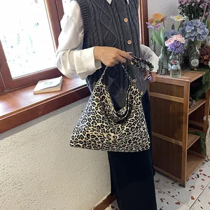 Detail view of large leopard print canvas tote bag on a model in a cozy indoor setting