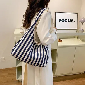 Grand sac fourre-tout en toile à rayures bleu marine et blanc porté par un mannequin