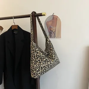 Detail view of the large leopard print canvas tote bag hanging on a wooden hanger