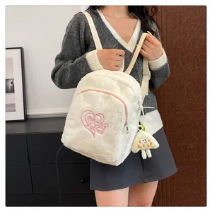 Close-up of plush white backpack with pink heart embroidery and cute cartoon charm